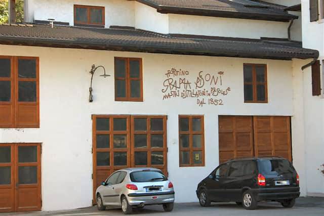 Edificio storico con garage e auto, firma e data visibili sulla facciata.