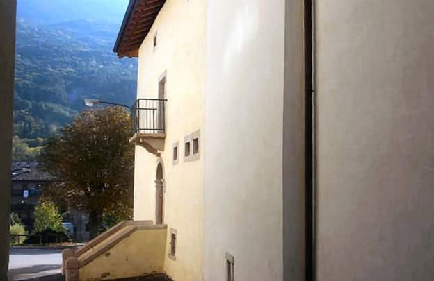 Facciata di una casa in stile tradizionale con balcone e vista sulle montagne.