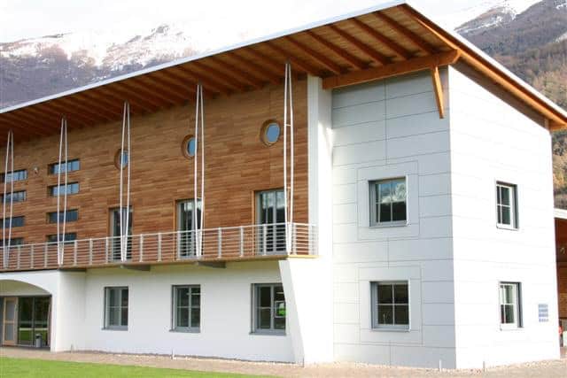 Edificio residenziale in legno e cemento con balconi e finestre moderne.
