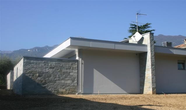 Casa moderna con pareti in pietra e tetto a sbalzo in stile contemporaneo.