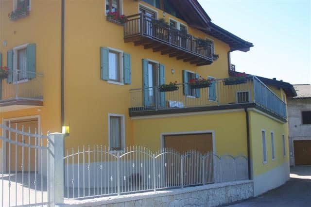 Edificio residenziale giallo con balconi e recinzione in ferro.