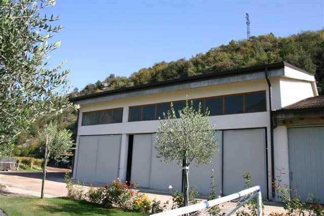 Edificio industrial a due piani con grandi finestre e ambiente naturale circostante.