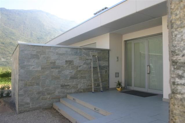 Ingresso di casa moderna con parete in pietra e porta scorrevole.