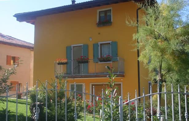 Casa di civile abitazione color giallo con balconi e giardino.