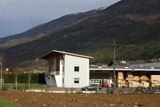 Edificio moderno in legno e cemento con paesaggio montano sullo sfondo.