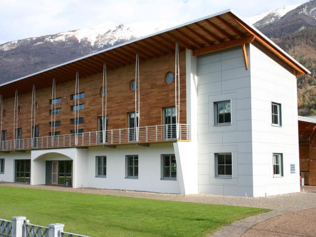 Edificio moderno in legno e cemento con vista sulle montagne.