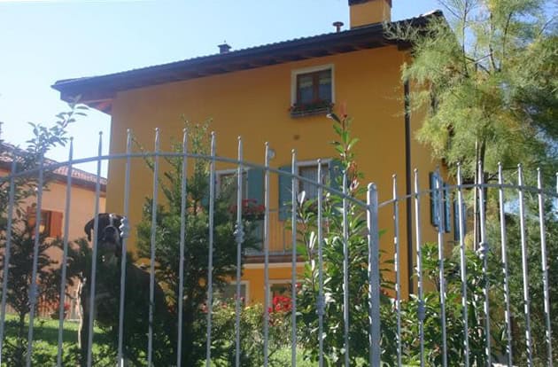 Casa di civile abitazione gialla con giardino e recinzione in ferro.