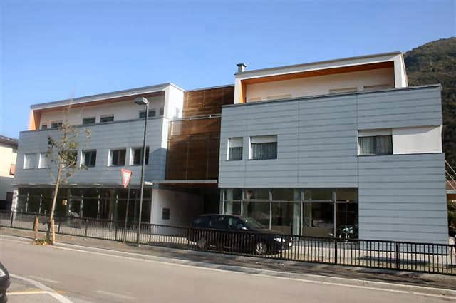 Edificio residenziale moderno con facciata in vetro e rivestimento in pannelli metallici.