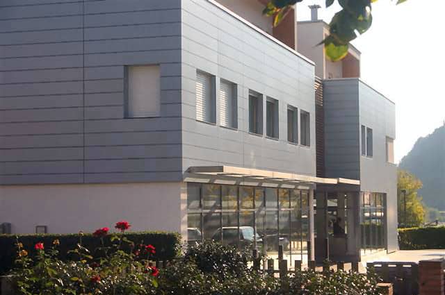 Edificio residenziale moderno con facciata in pannelli di metallo e grandi vetrate.