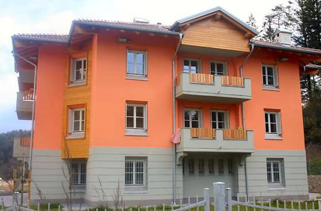 Edificio residenziale in stile moderno con balconi e facciata colorata in arancione e beige.