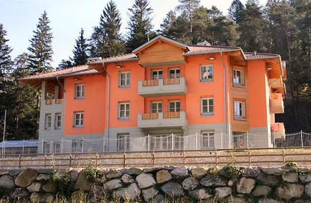 Edificio residenziale in stile alpino con balconi e tetto spiovente.