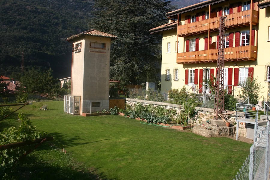 Edificio residenziale con giardino e torretta in zona verde.