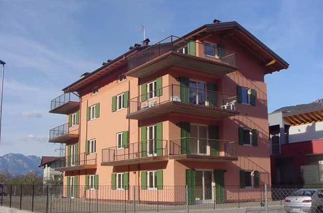 Edificio residenziale a più piani con balconi e finestre verdi, in zona tranquilla.