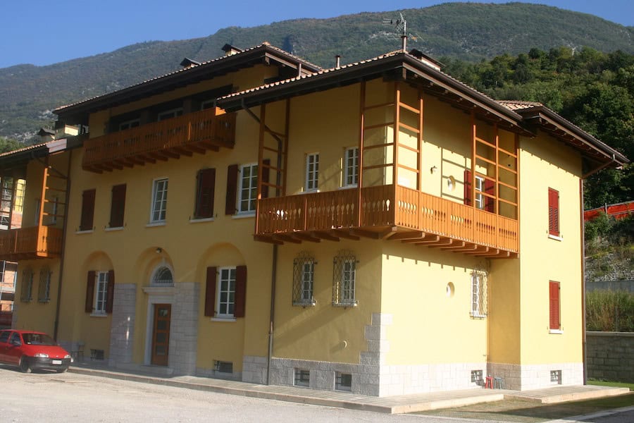 Edificio residenziale in stile tradizionale con balconi in legno e facciata gialla.