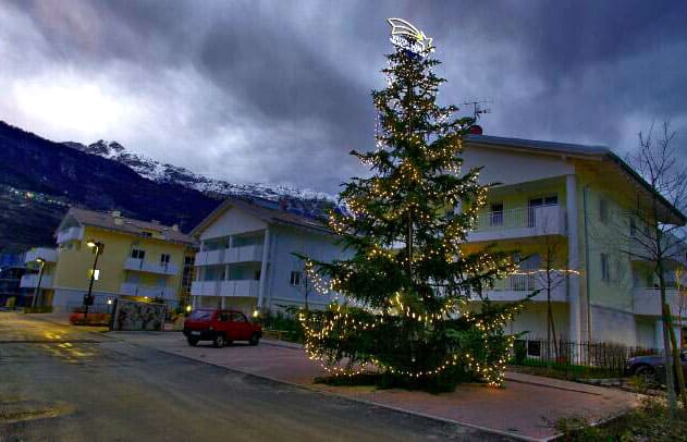 Albero di Natale decorato con luci in un cortile residenziale.