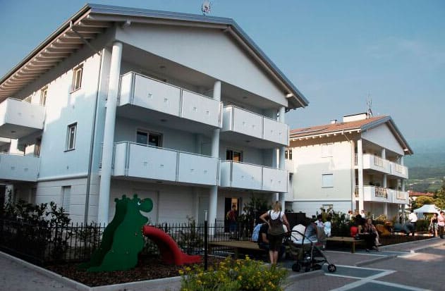 Edificio residenziale moderno con balconi e area giochi esterna.