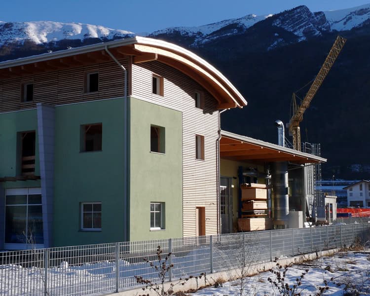 Edificio residenziale in costruzione con montagne sullo sfondo.