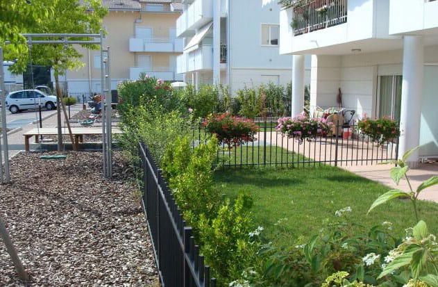 Giardino condominiale con area giochi e piante vicino a residenza moderna.