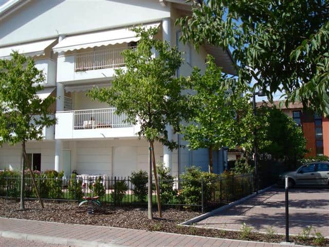 Residenza EOS edificio moderno con balconi e giardino ben curato.