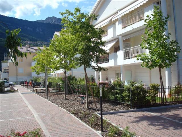 Edificio moderno con balconi e giardino ben curato.