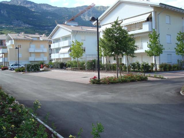 Complesso residenziale moderno con spazi verdi e parcheggi.