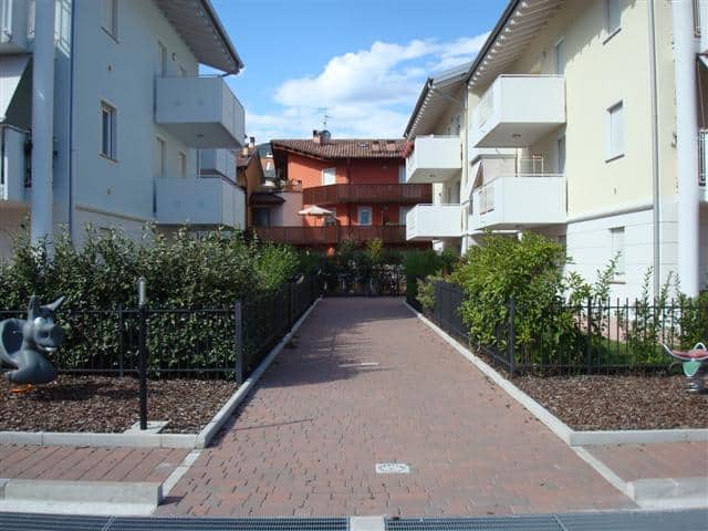 Edificio residenziale con giardini e vialetti pavimentati.