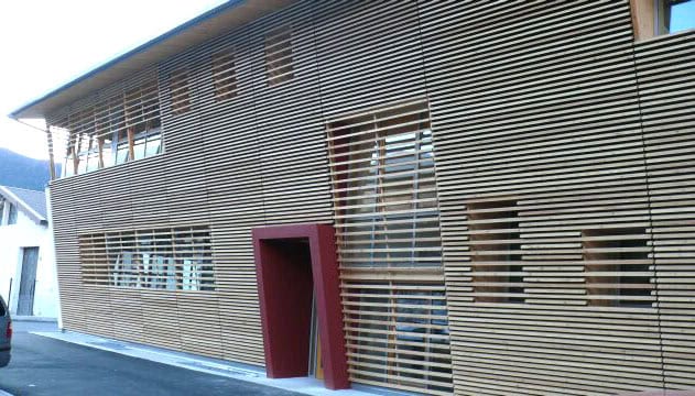 Edificio moderno con rivestimento in listelli di legno e porta rossa.