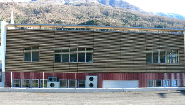 Edificio moderno in legno e mattoni con vista montagna sullo sfondo.