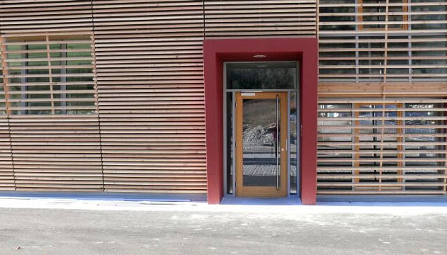 Facciata moderna con pannelli di legno e ingresso in vetro.