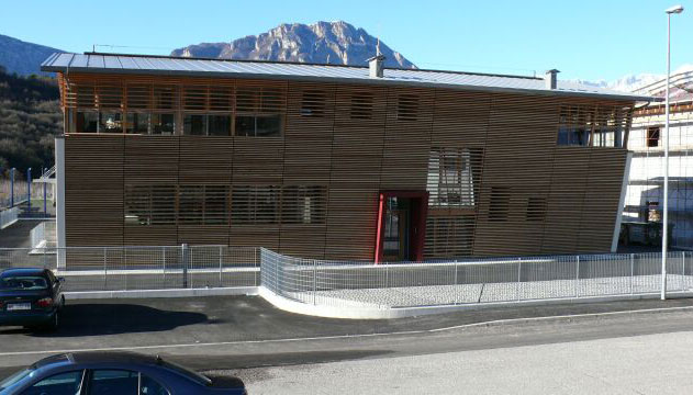 Edificio moderno in legno con grandi finestre e tetto inclinato.