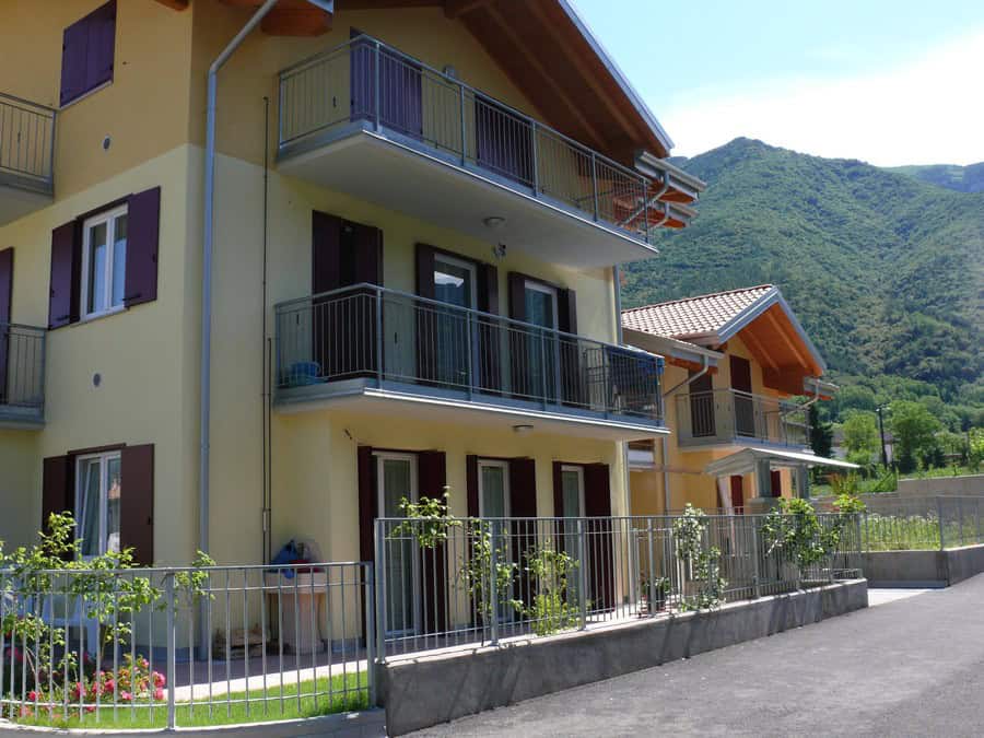Edificio residenziale a tre piani con balconi e recinzione in metallo.