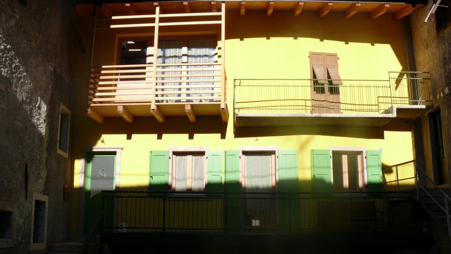 Facciata di edificio residenziale con balconi e persiane verdi.