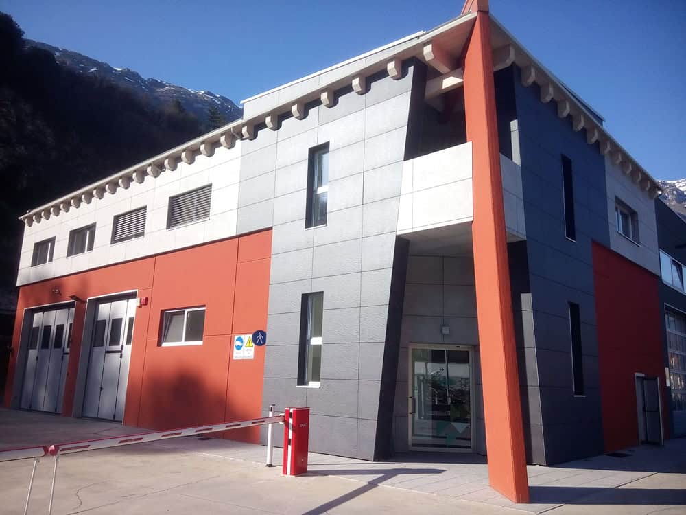 Edificio moderno con facciata in grigio e rosso, situato in montagna.