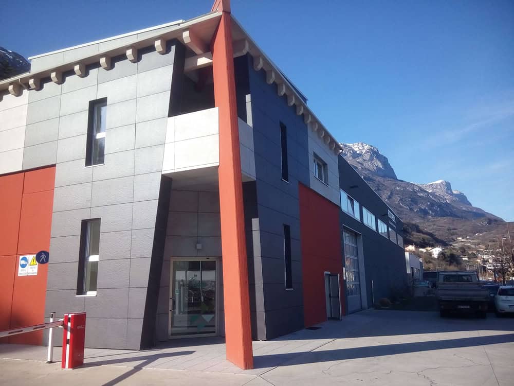 Edificio moderno di Costruzioni Dallapè Srl con montagne sullo sfondo.