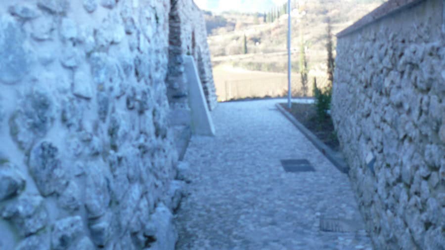 Sentiero nel cimitero di Lasino con muretti in pietra e pavimentazione in ciottoli.