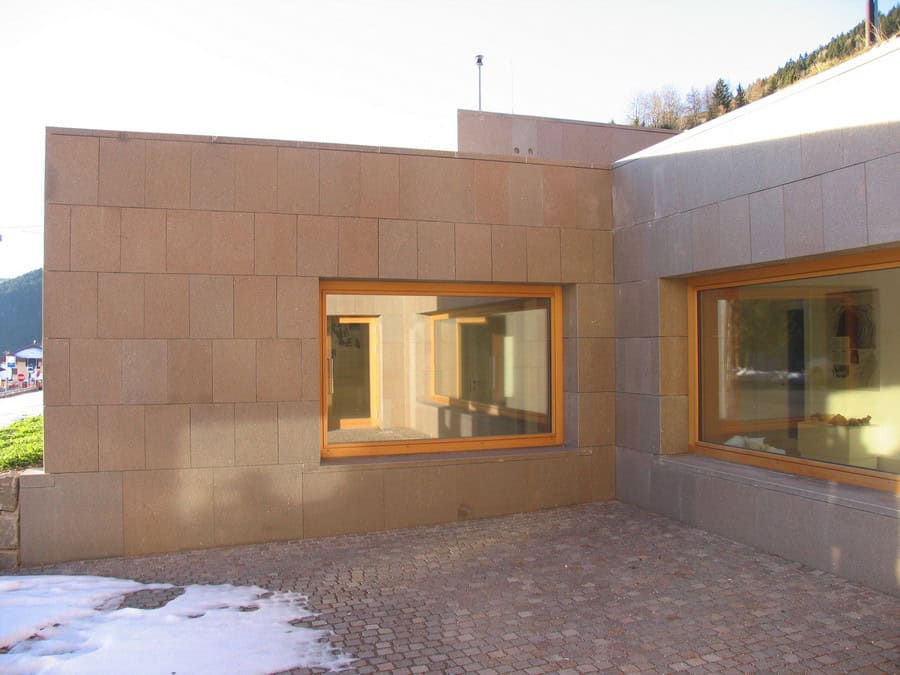 Costruzioni Dallapè Srl edificio moderno con grandi finestre e pareti in pietra naturale.