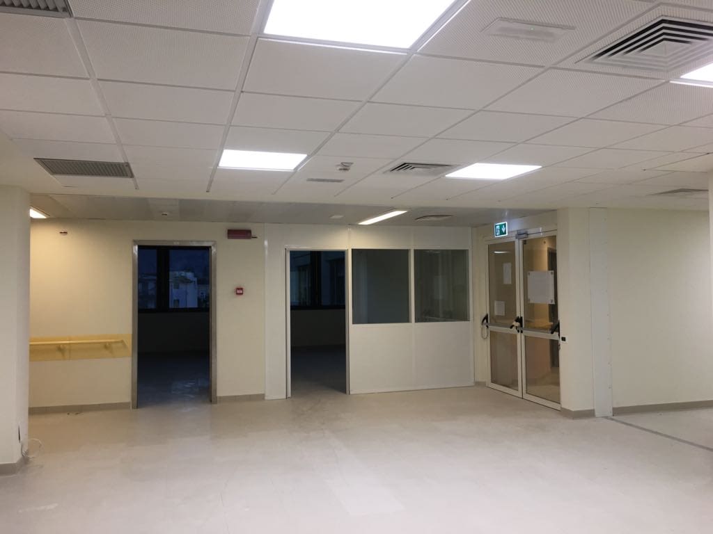 Interno di un ospedale con pareti bianche e porte in vetro.