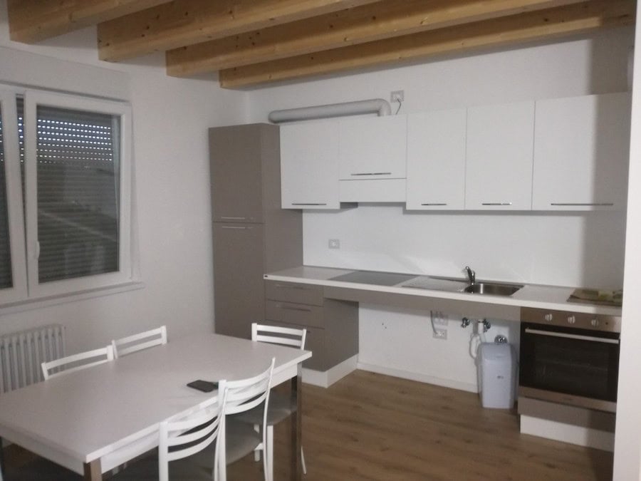Cucina moderna con mobili bianchi e elettrodomestici in un ambiente luminoso.
