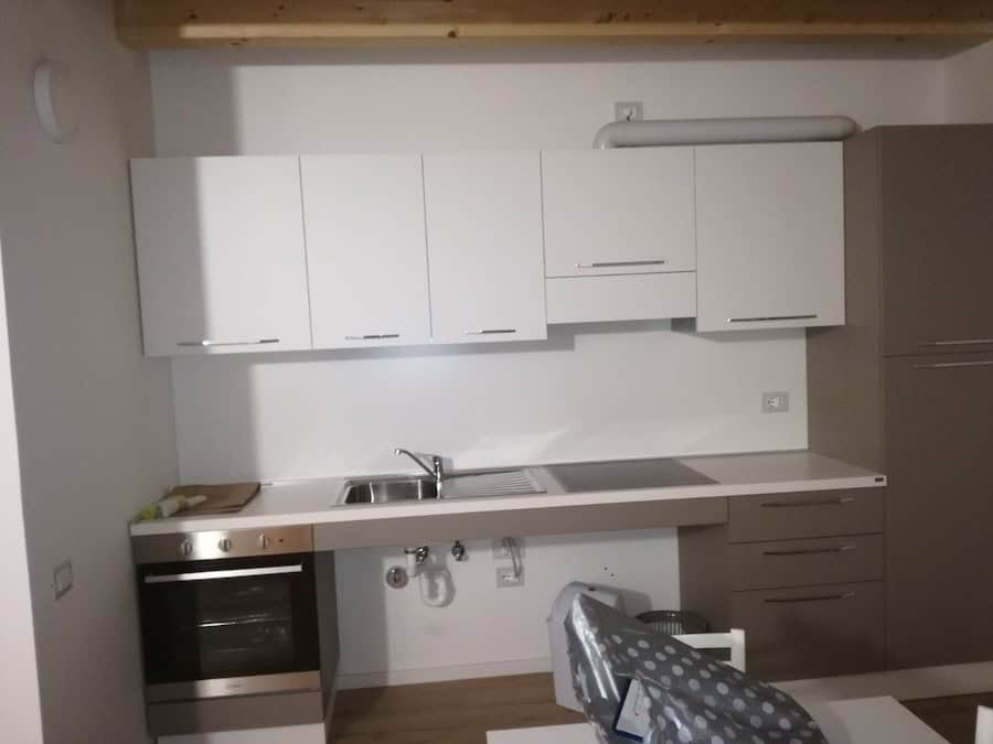 Cucina moderna con mobili bianchi e piano in granito, vista da vicino.
