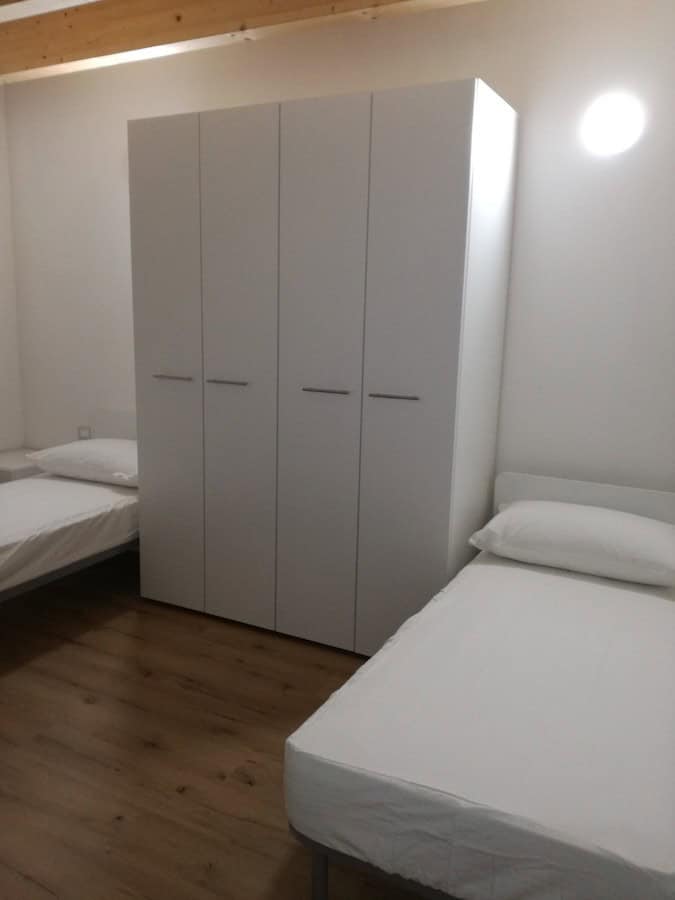 Camera da letto con armadio bianco e due letti singoli.