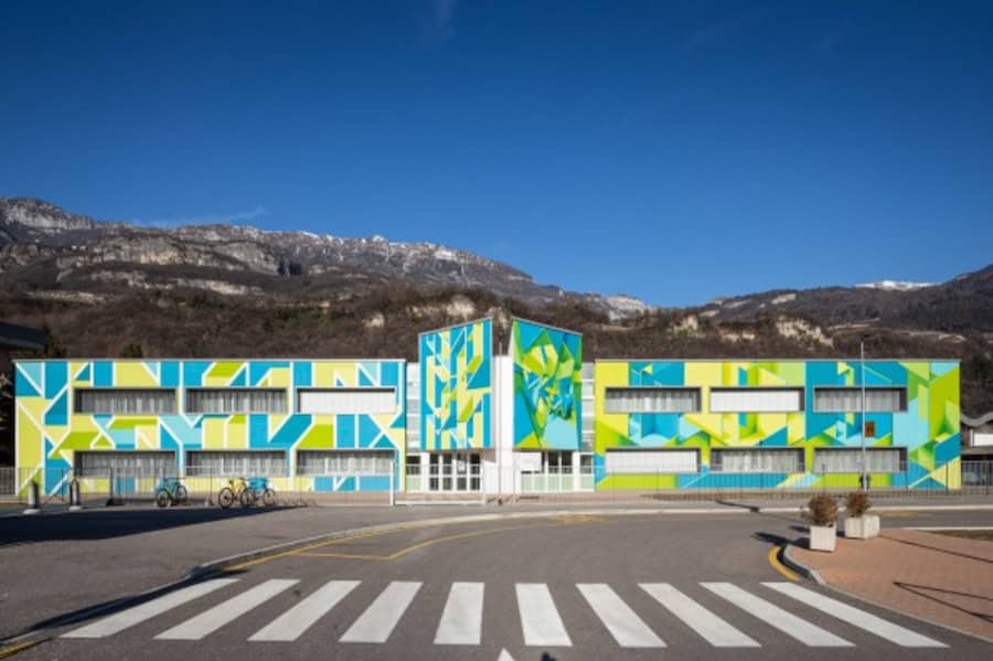 Edificio moderno con facciata colorata e montagne sullo sfondo.