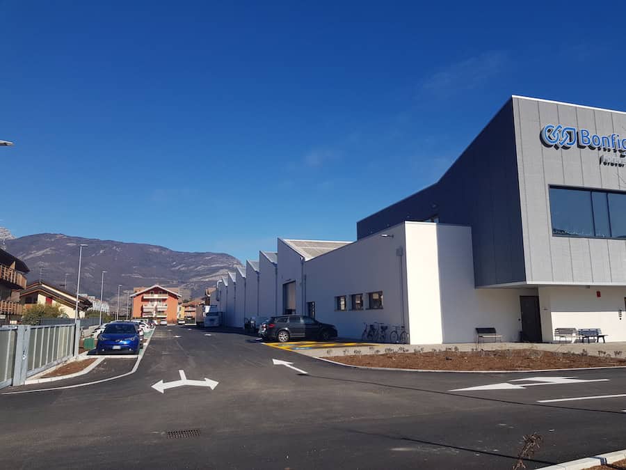 Capannone industriale Bonfiglioli a BMR con parcheggio e montagne sullo sfondo.