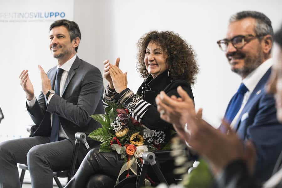 Persone in un evento di lavoro, sorridenti e applaudendo, in un ambiente professionale.