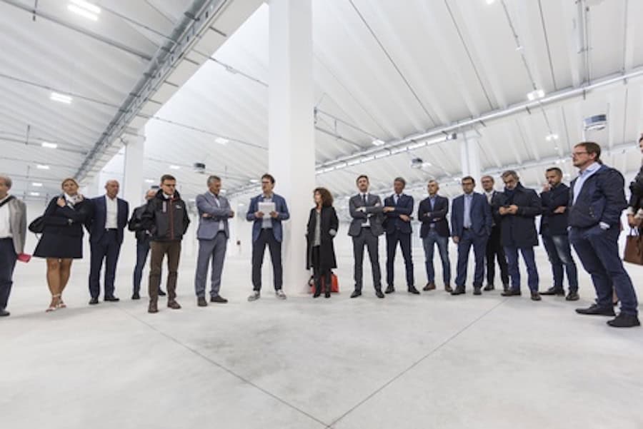 Gruppo di persone in visita a un capannone industriale moderno.
