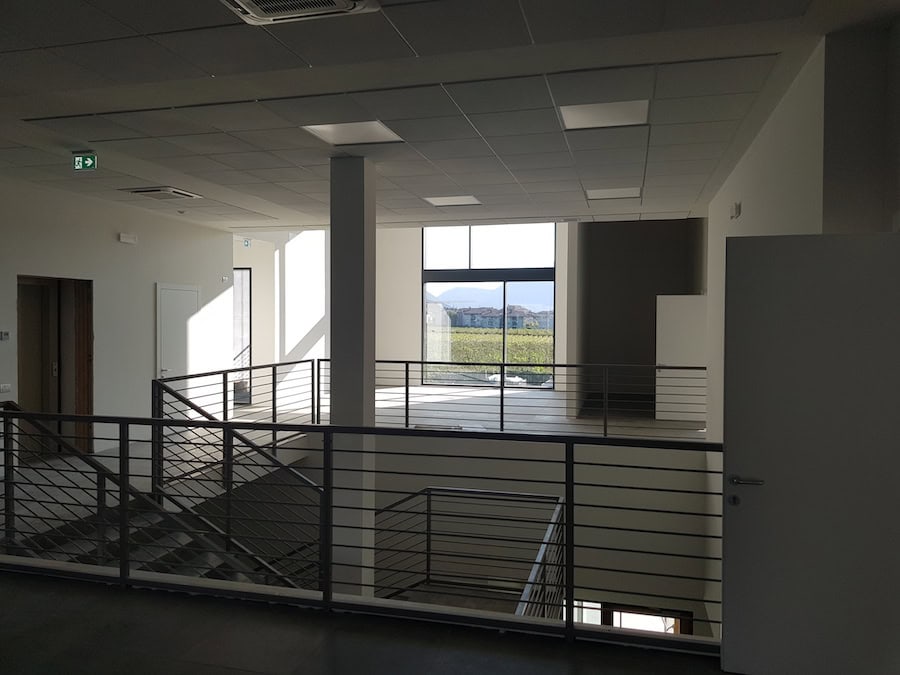 Interni moderni di un capannone industriale con balcone e grandi finestre.