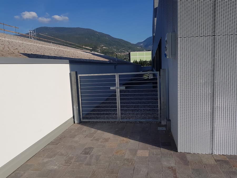 Ingresso di un capannone industriale con cancello in metallo e pareti in lamiera.