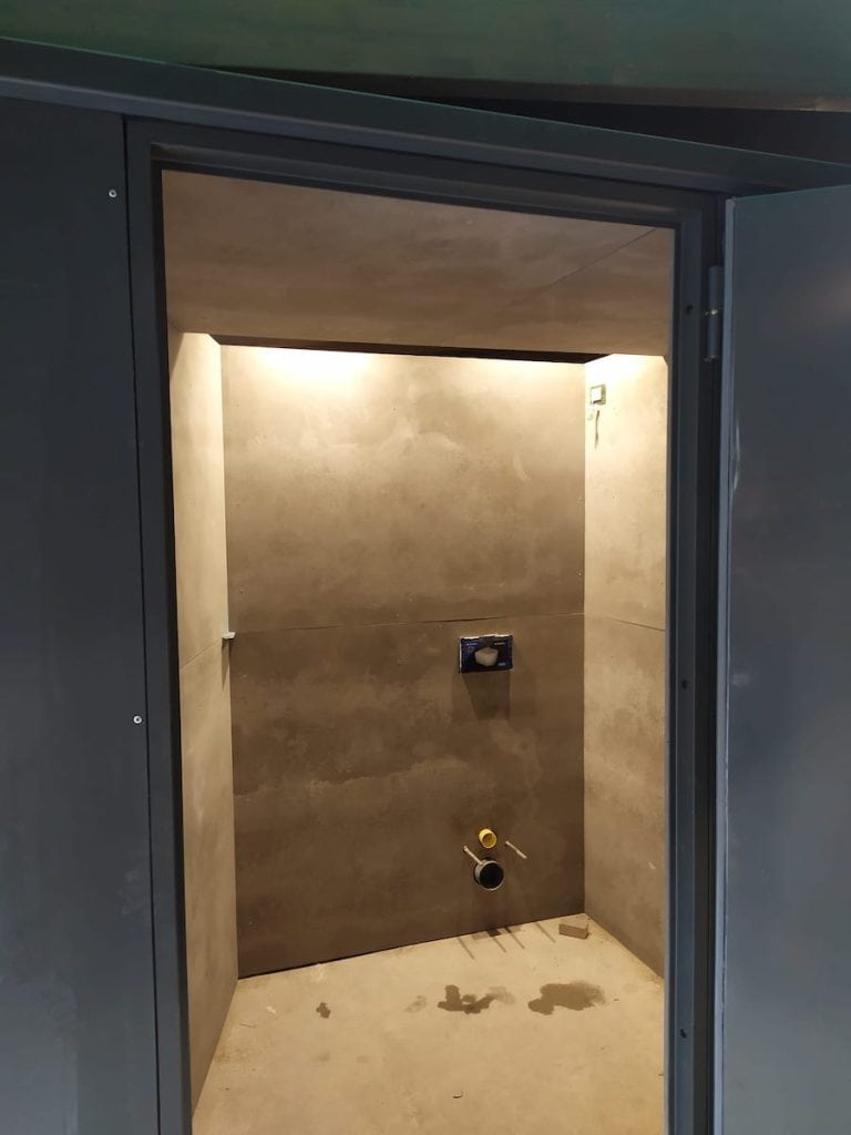 Interno di un bagno in costruzione con pareti in gres e impianto idraulico.
