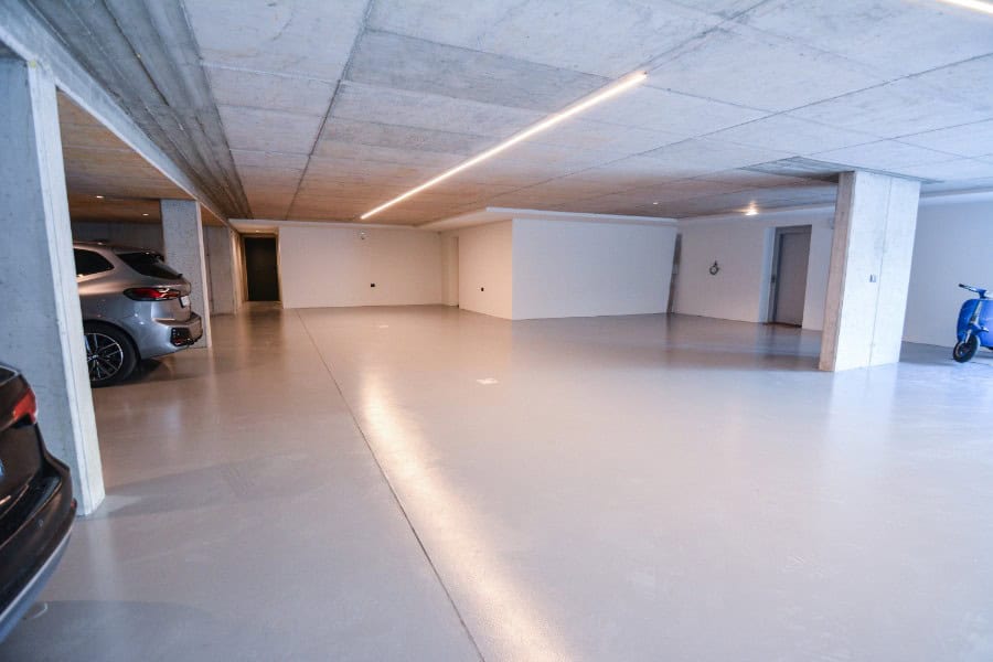 Parcheggio sotterraneo moderno con auto e moto, spazio ampio e luminoso.