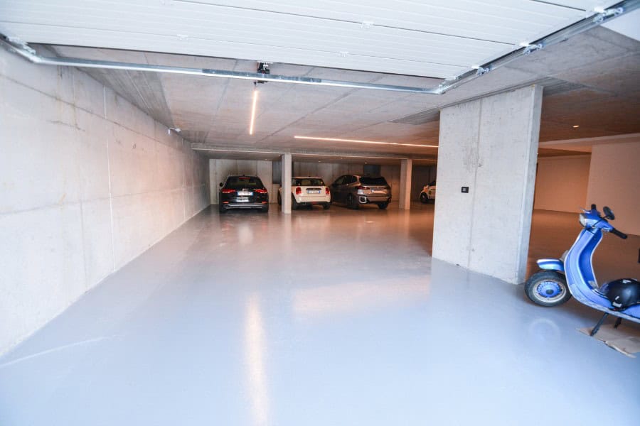 Parcheggio sotterraneo moderno con auto e scooter in Residenza Privata Malcesine.