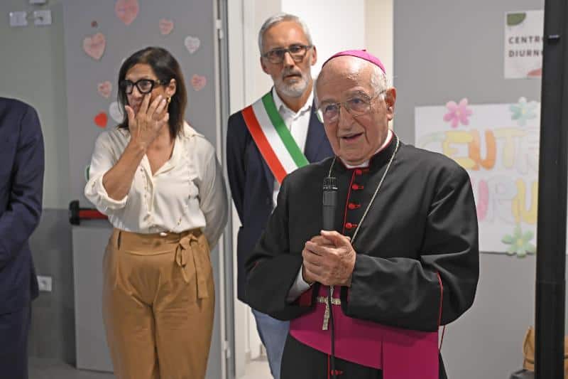 Immagine di un evento con un vescovo e due persone in un ambiente interno.